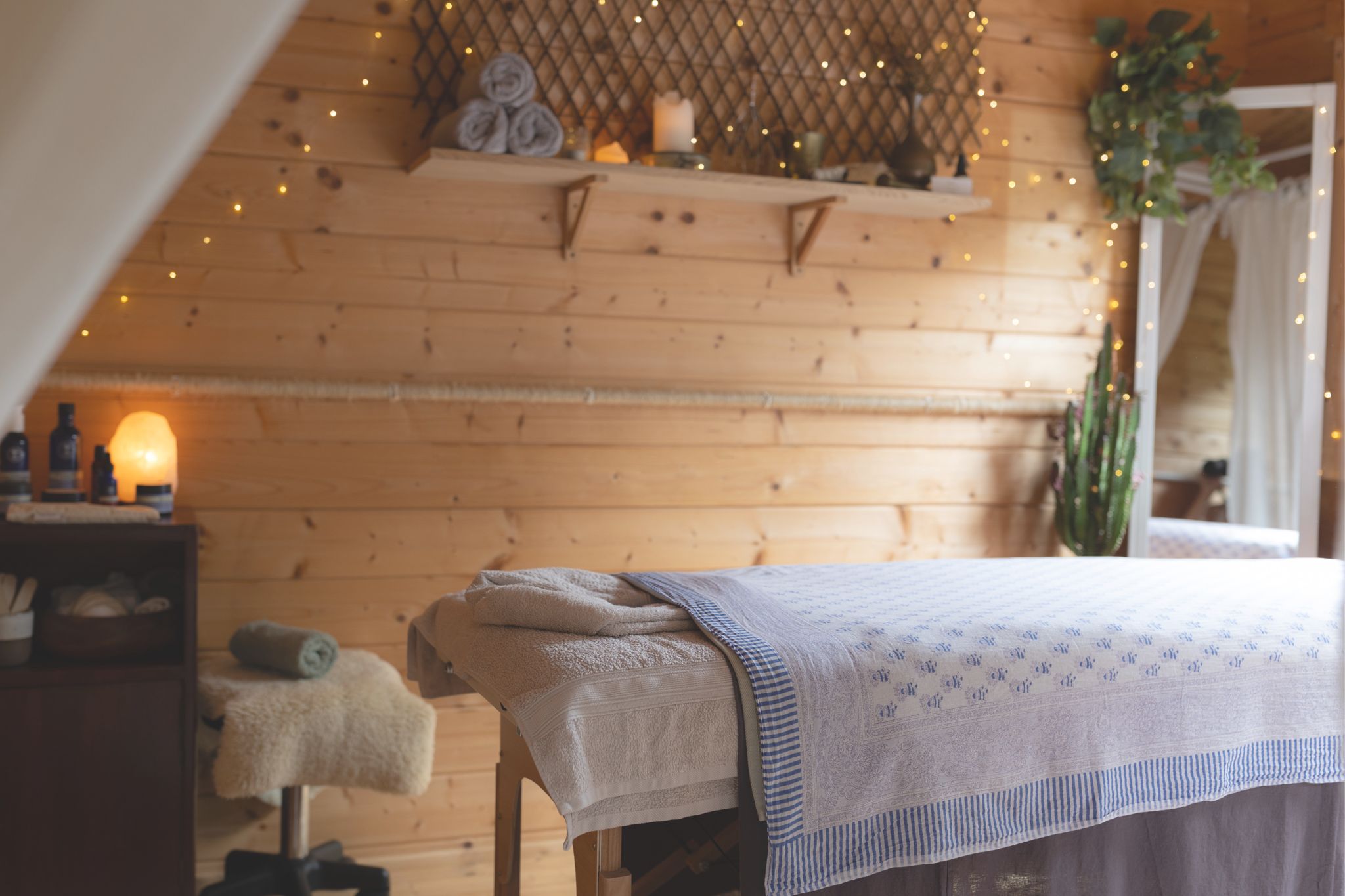 Cozy massage bed in a wooden hut with soft lighting.
